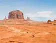 Desert landscape in Monument Valley, Utah with iconic red rock formations and wide open plains under a clear blue sky