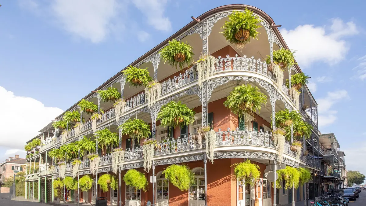 Historic French Quarter building in New Orleans with wrought-iron balconies and hanging plants.