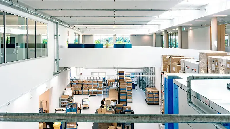 Blick in das Logistikzentrum von Sutter Medizintechnik mit hohen Decken, Lagerräumen, Regalen und moderner, lichtdurchfluteter Architektur.