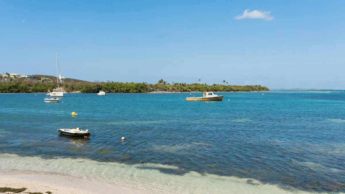 Coastline in Fajardo, Puerto Rico, with turquoise water, sandy beach, and small anchored boats.