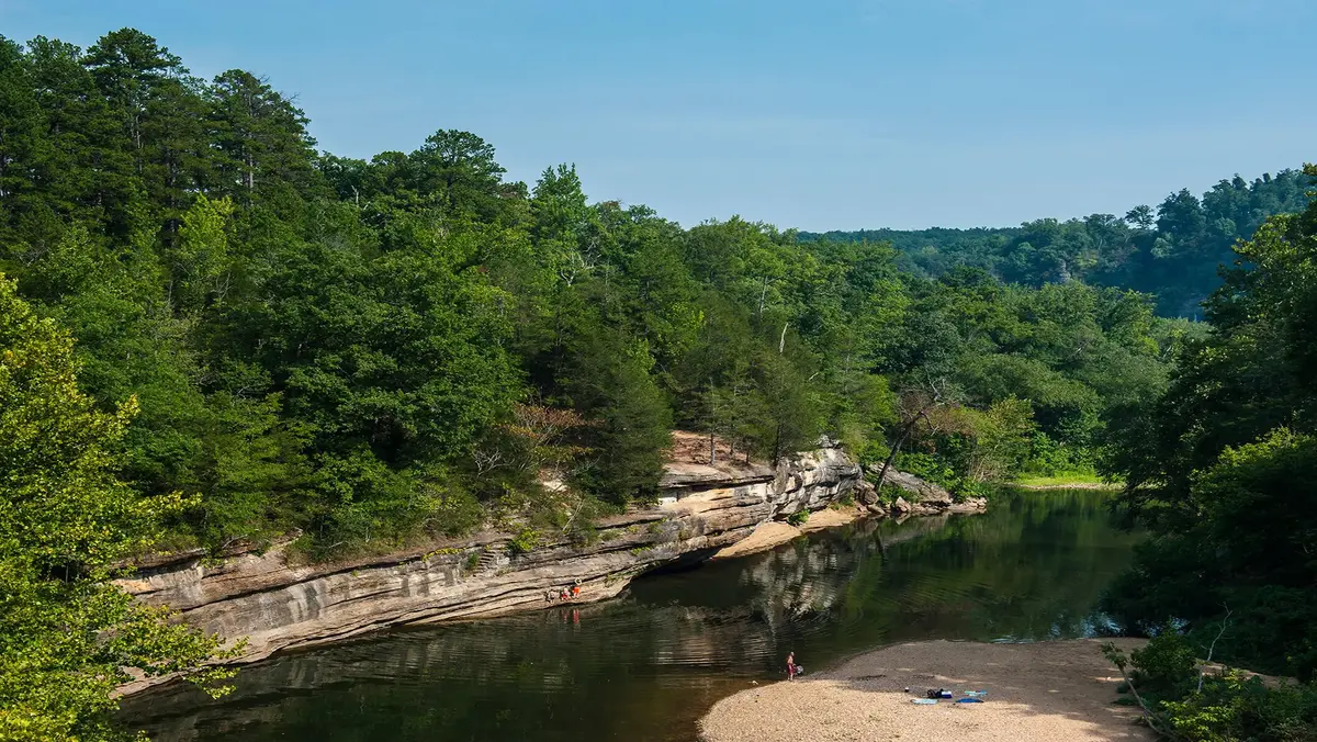 River landscape in the Ozarks with forested hills, rocky shoreline, and calm water