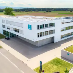 Luftaufnahme des modernen Firmengebäudes von Sutter Medizintechnik in Emmendingen mit Blick auf das Umfeld und angrenzende Felder.        ChatGPT fragen