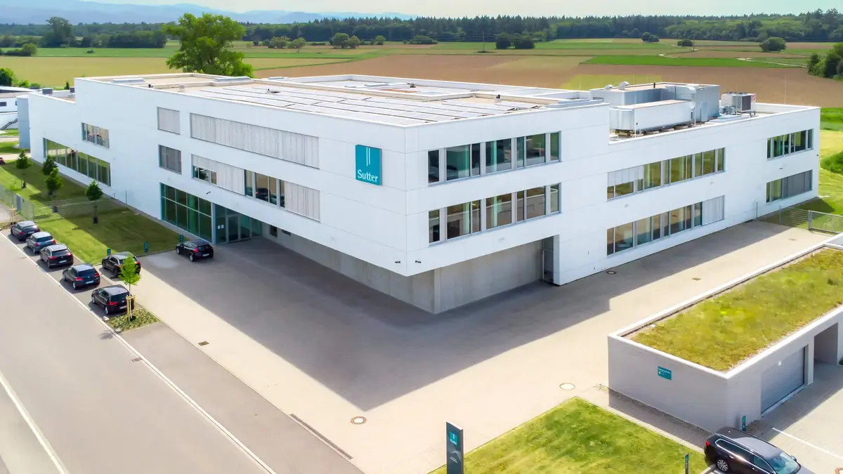 Luftaufnahme des modernen Firmengebäudes von Sutter Medizintechnik in Emmendingen mit Blick auf das Umfeld und angrenzende Felder.        ChatGPT fragen
