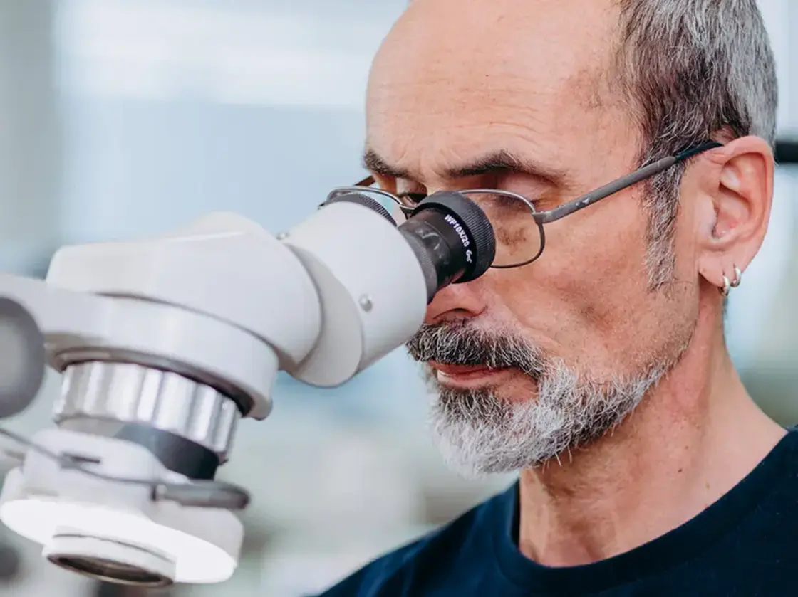 sutter-feinmechanik-mikroskoparbeit.jpg Mitarbeiter von Sutter Medizintechnik bei der Arbeit mit einem Mikroskop – Fokus auf feinmechanische Präzision in der Instrumentenfertigung